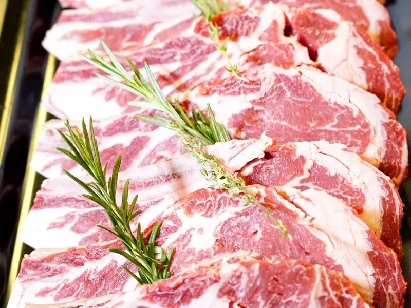 Raw beef steaks with rosemary on a board